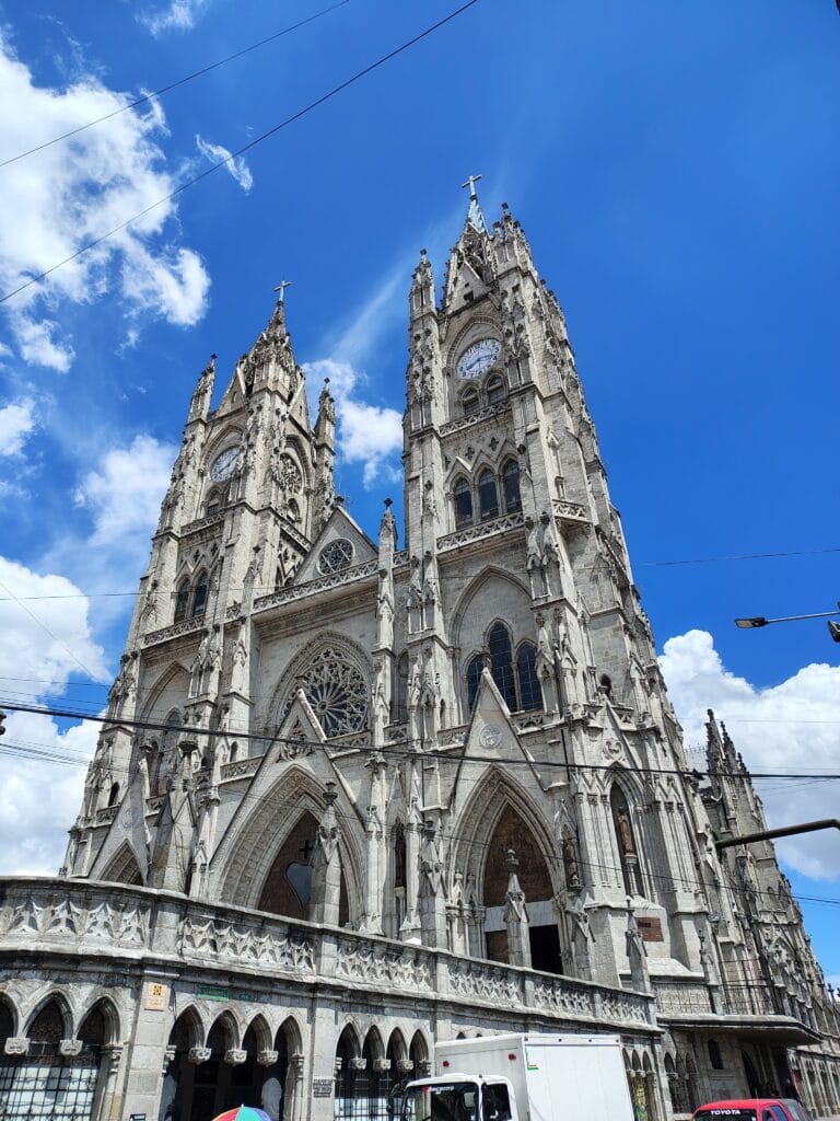 The neo-Gothic Basilica del Voto Nacional rising above the streets of Quito under a bright blue sky.
