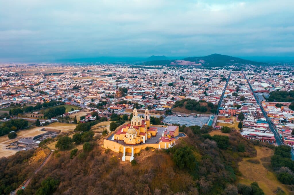 Ancient ruins of the Cholula Archaeological Site with the Great Pyramid and Nuestra Señora de los Remedios Church in Puebla, Mexico.