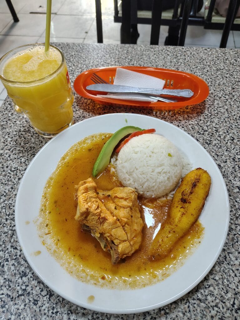 Traditional Ecuadorian lunch with chicken, rice, fried plantain, avocado, and fresh juice served at a local restaurant in Quito.