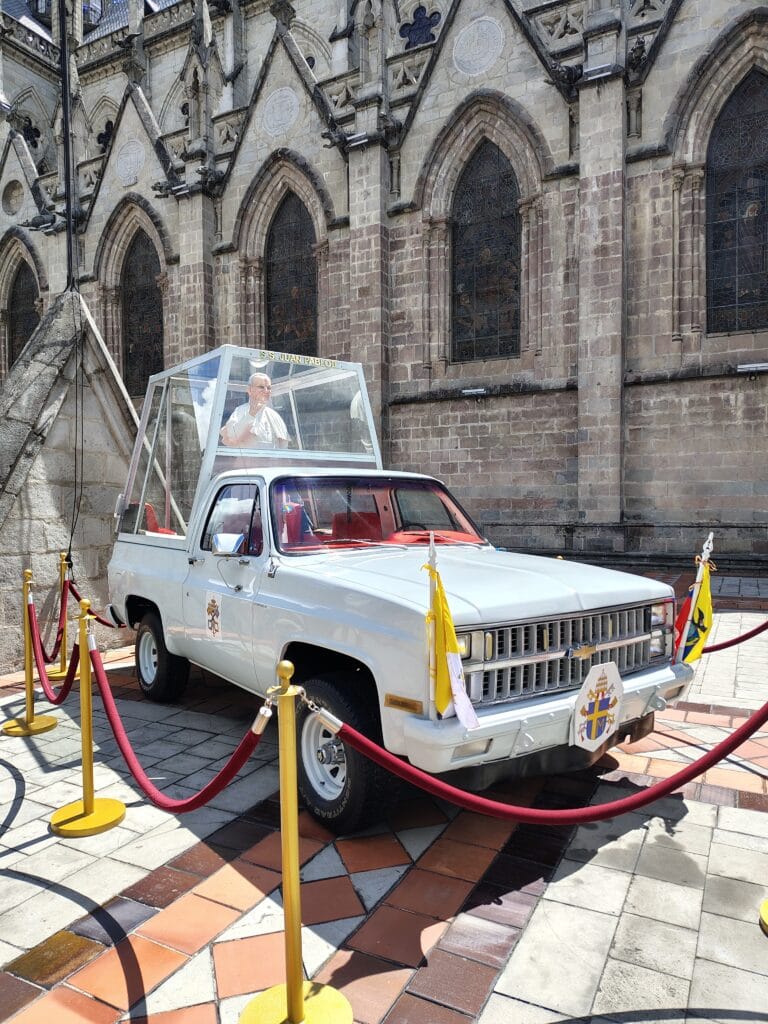 The preserved Popemobile used during Pope John Paul II's visit to Ecuador displayed beside Basilica del Voto Nacional.