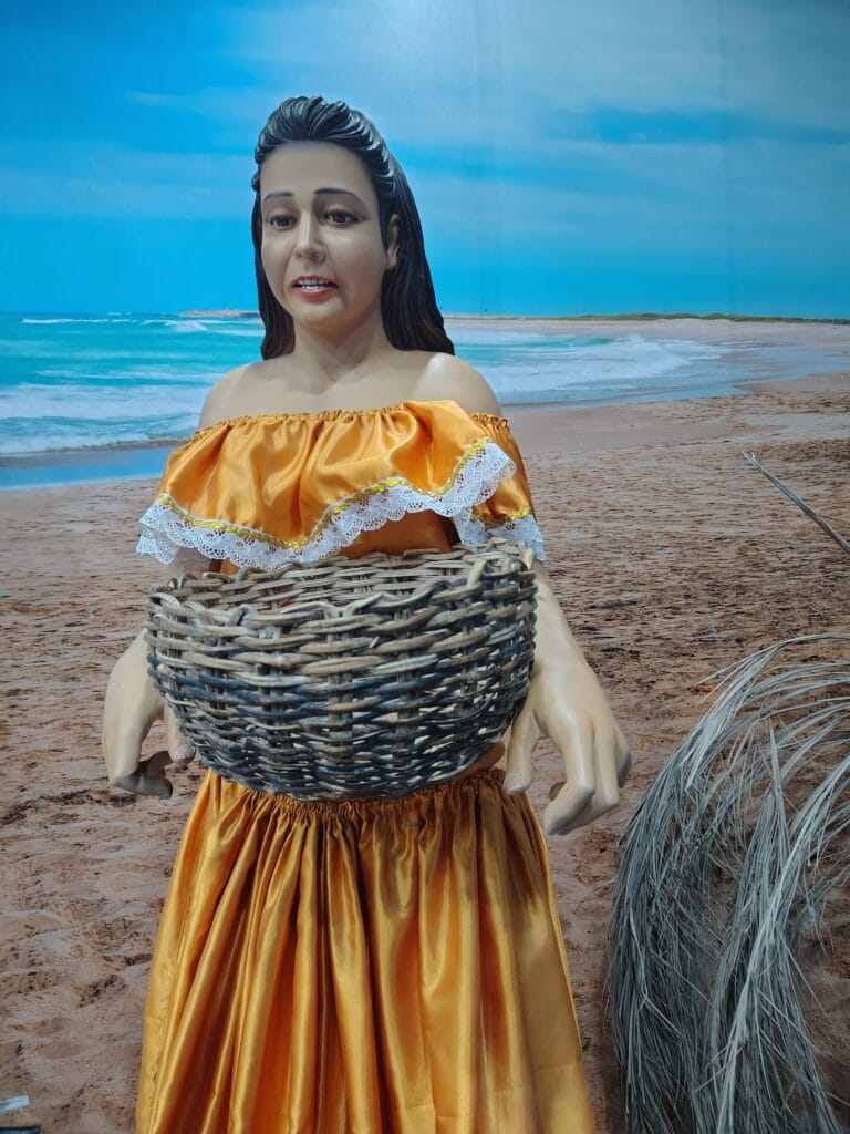 Indigenous woman carrying a woven basket in a museum exhibit at Mitad del Mundo.