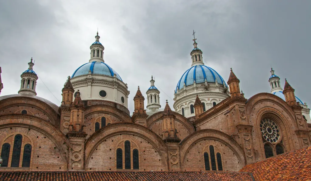 The blue-tiled domes of the Cathedral of the Immaculate Conception in Cuenca, Ecuador, under a cloudy sky
