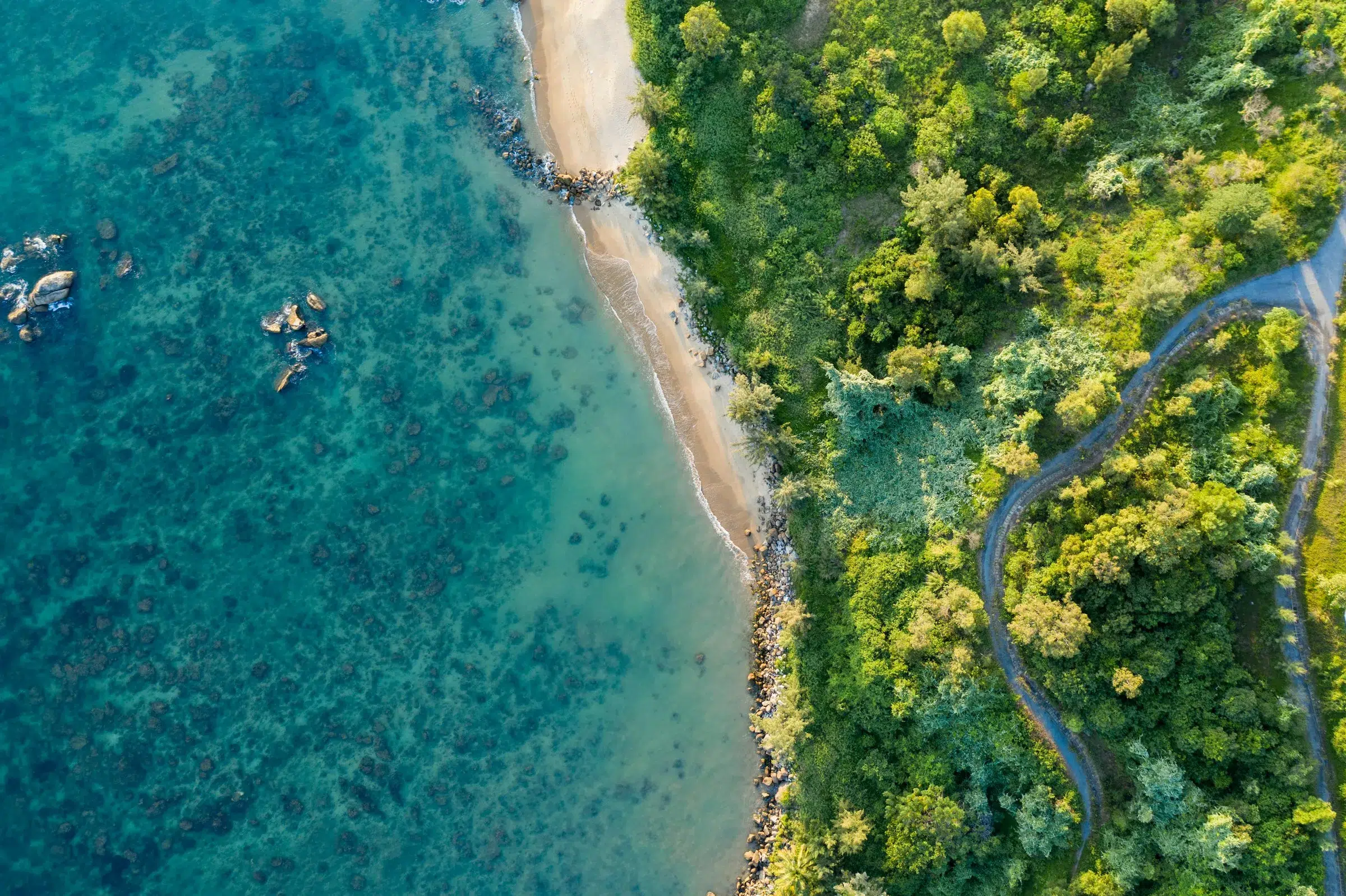 Aerial view of Da Nang's long sandy coastline with turquoise water and green hills in central Vietnam