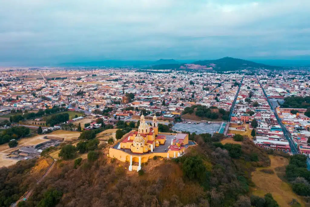Ancient ruins of the Cholula Archaeological Site with the Great Pyramid and Nuestra Señora de los Remedios Church in Puebla, Mexico.