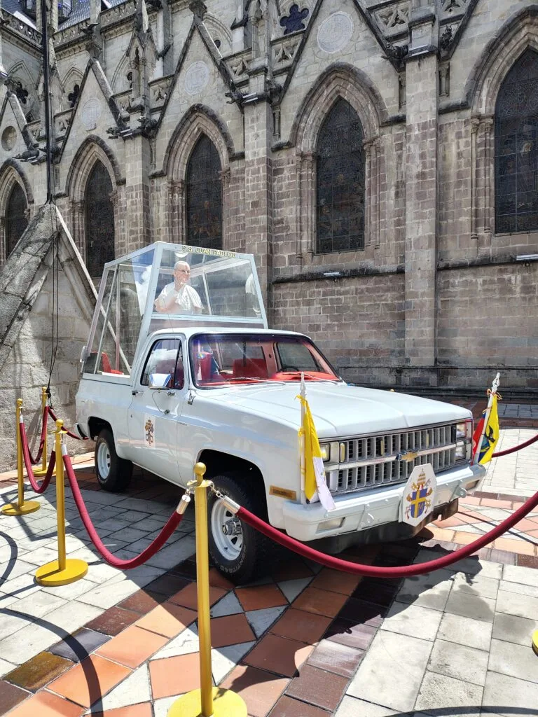The preserved Popemobile used during Pope John Paul II's visit to Ecuador displayed beside Basilica del Voto Nacional.